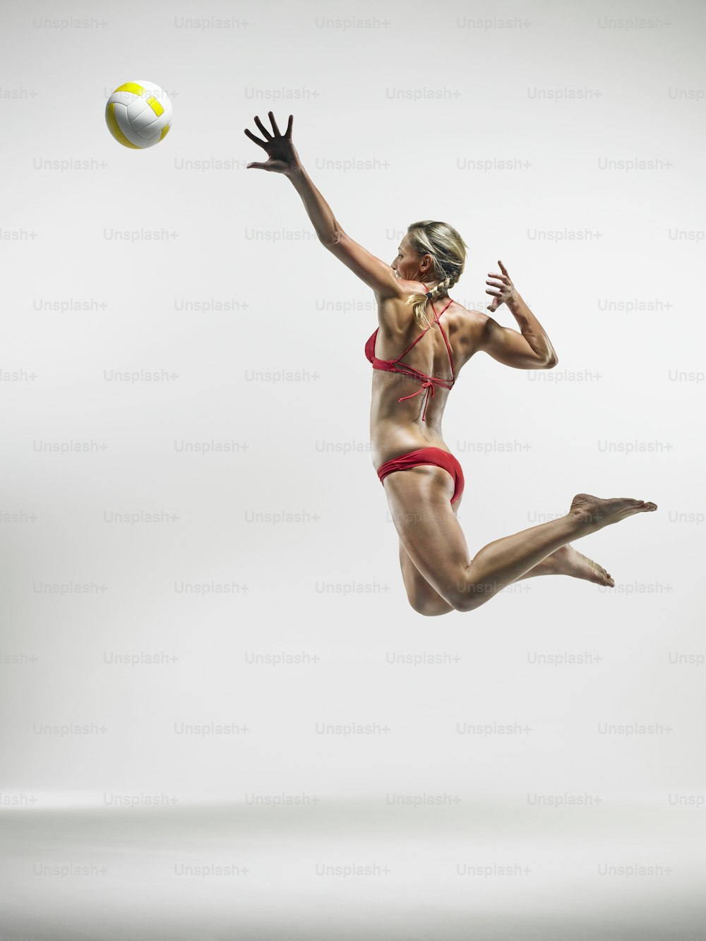 a woman in a bikini jumps to catch a ball