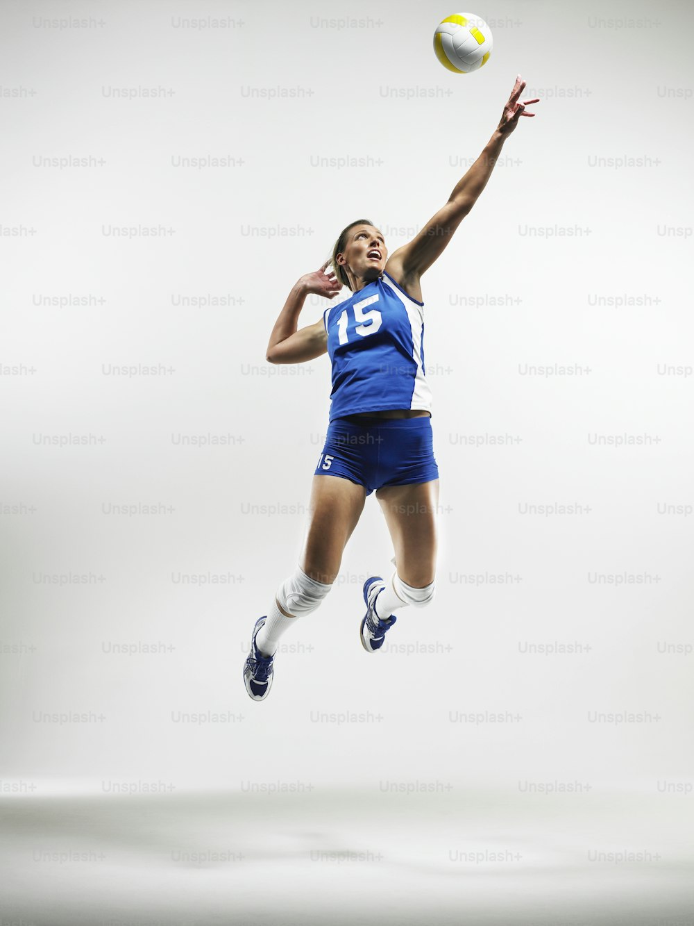a woman jumping in the air to catch a volleyball