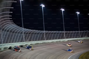 a group of cars driving around a track at night