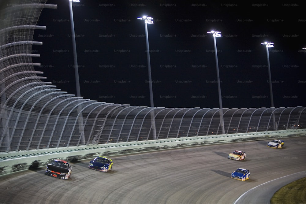 a group of cars driving around a track at night