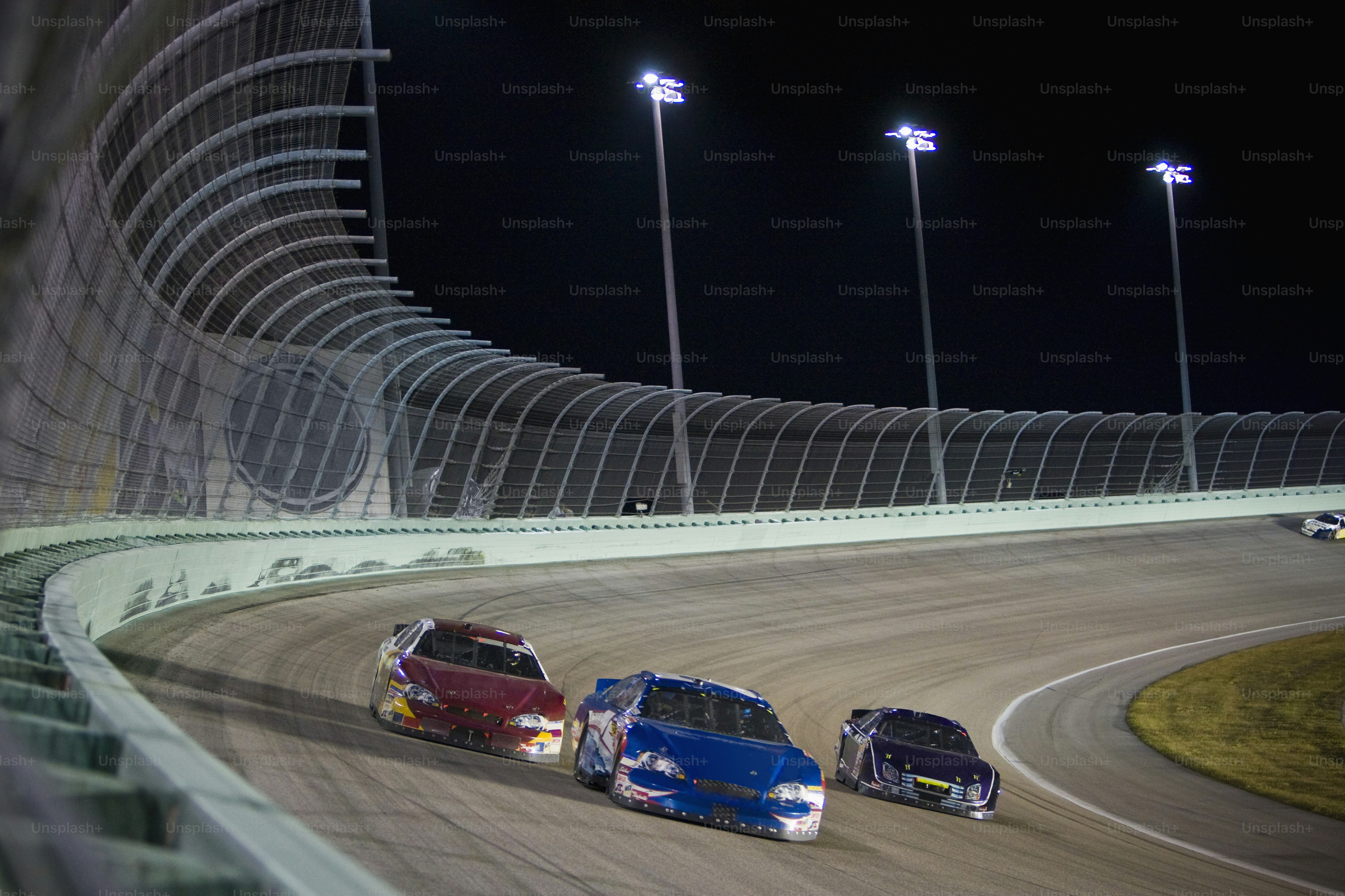 three cars racing on a track at night