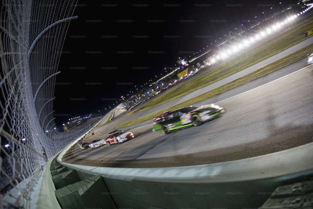 a group of cars driving around a track at night