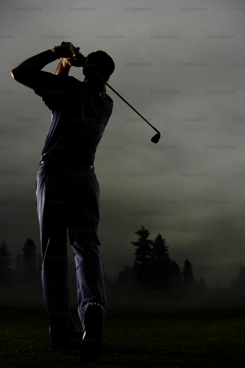a man swinging a golf club on a foggy day