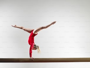 a woman is doing a handstand on a beam