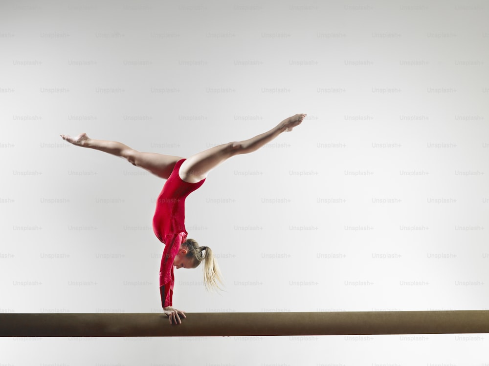 a woman is doing a handstand on a beam