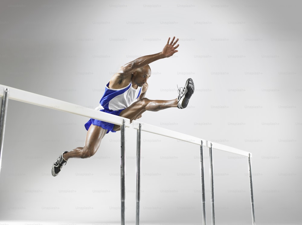a man running over a hurdle on a track
