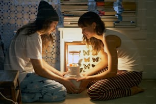 two girls sitting on the floor in front of a light