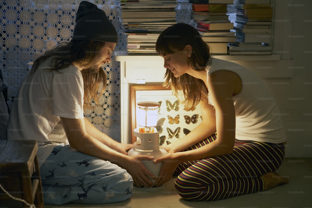 two girls sitting on the floor in front of a light