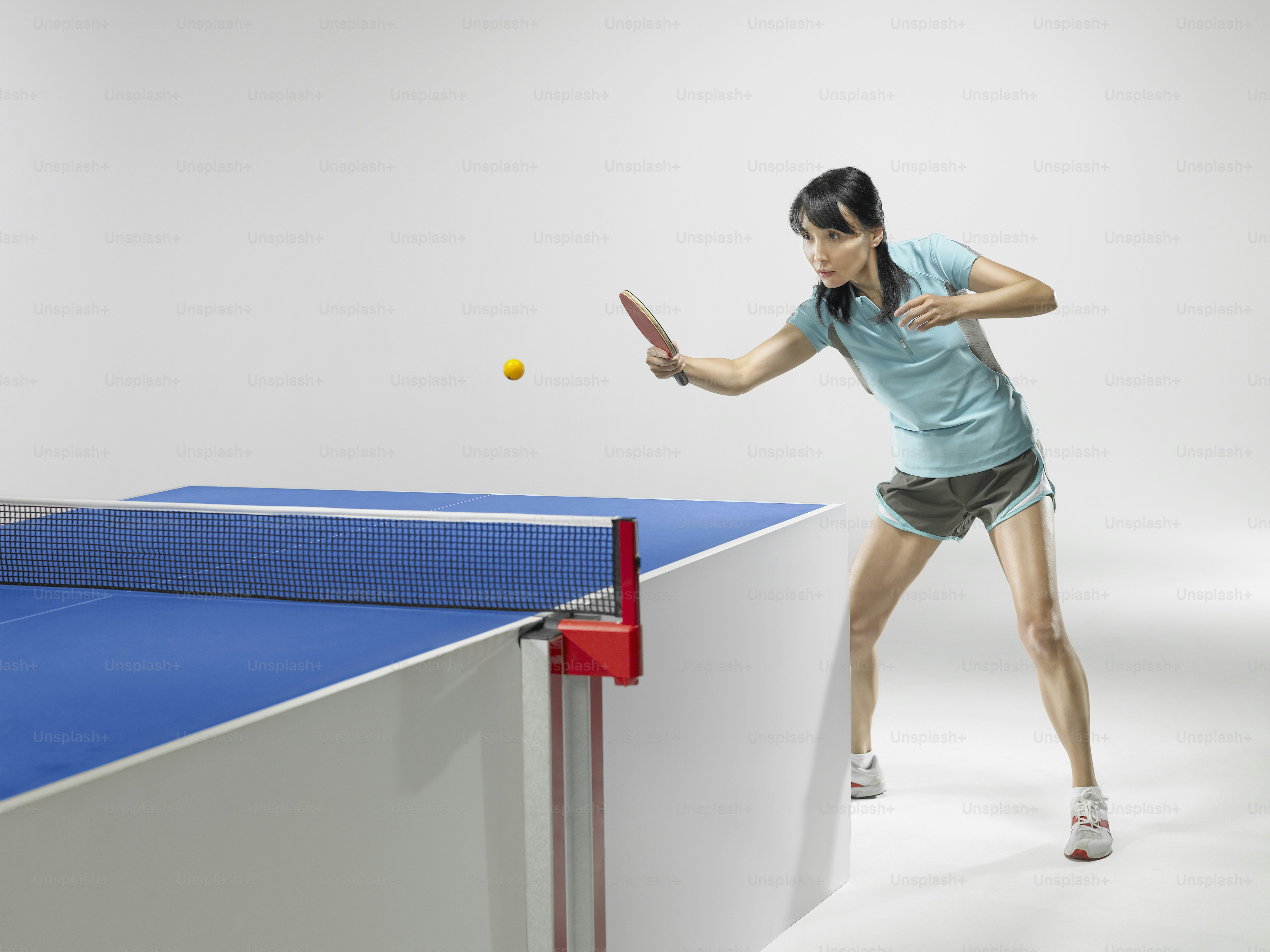 ラケットでテニスボールを打つ女性
