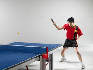 a man holding a tennis racquet on top of a ping pong table