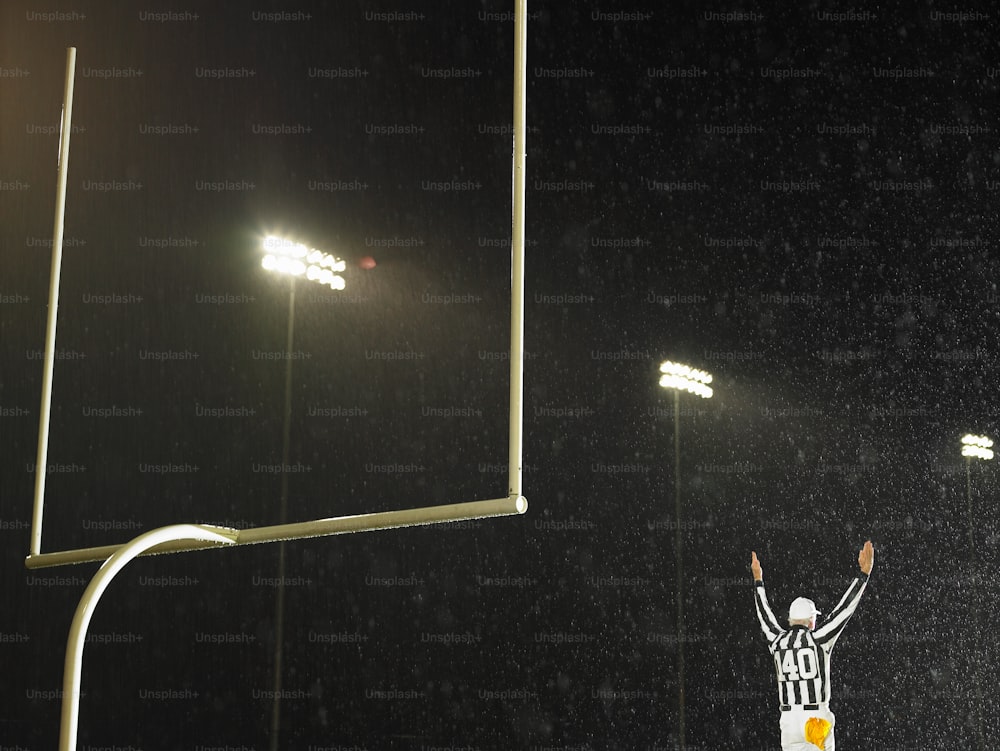 une personne debout devant un but de football la nuit