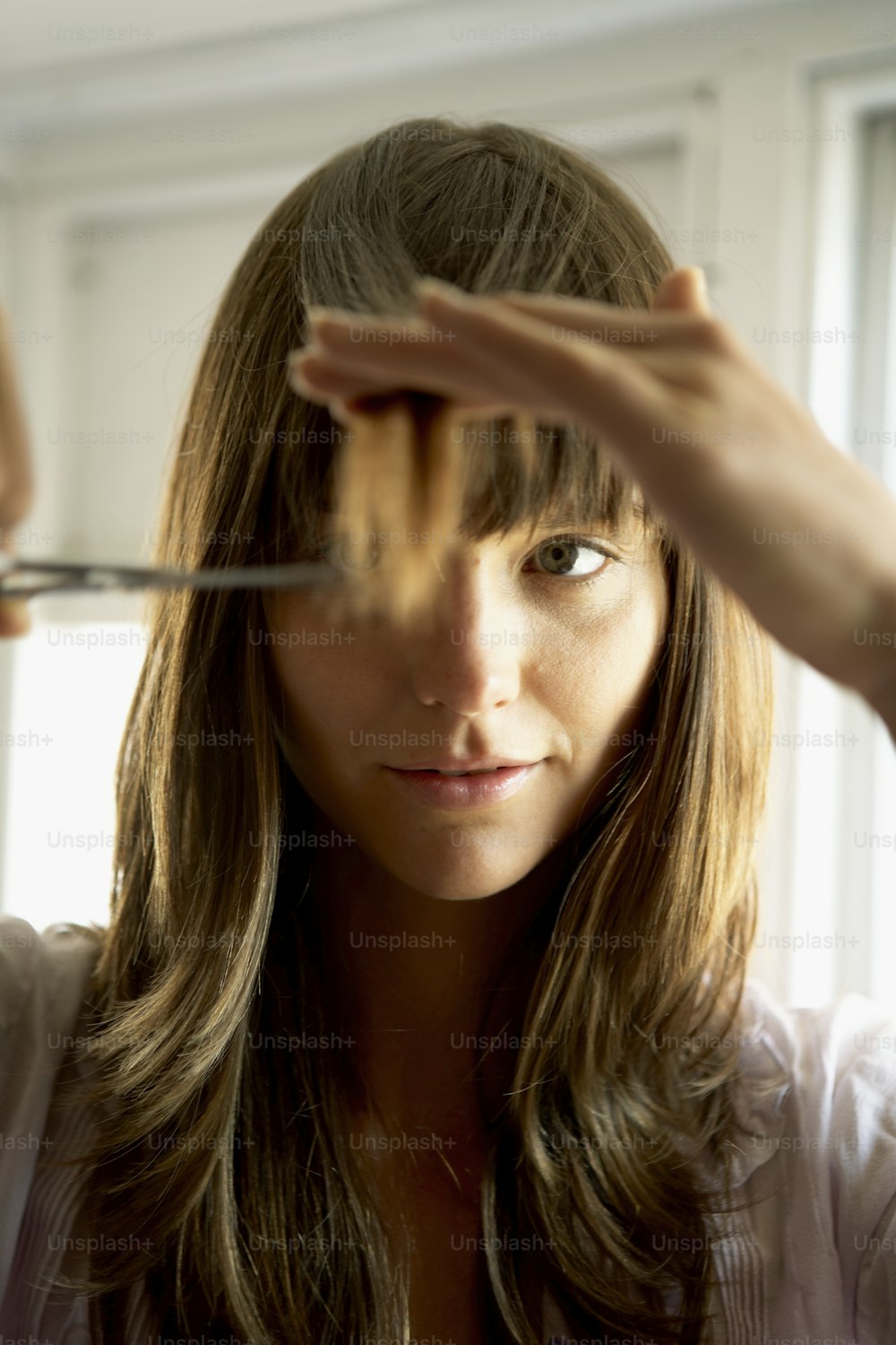 Una donna si taglia i capelli con le forbici
