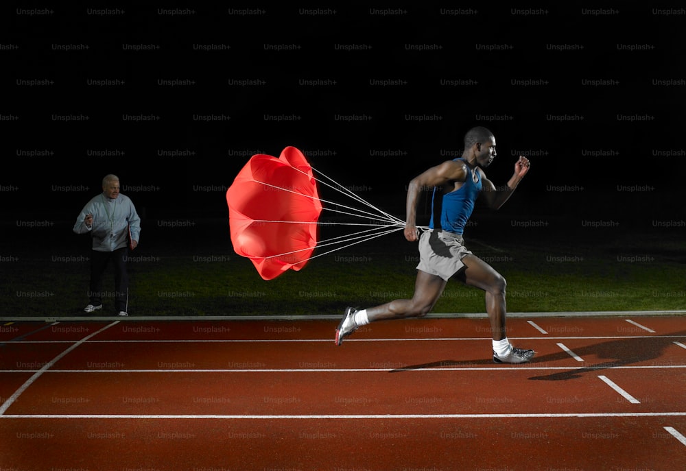 um homem correndo em uma pista com um paraquedas