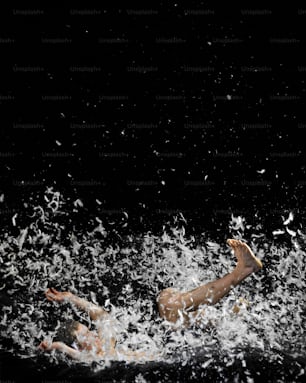 a man swimming in the water with a bunch of white confetti all around
