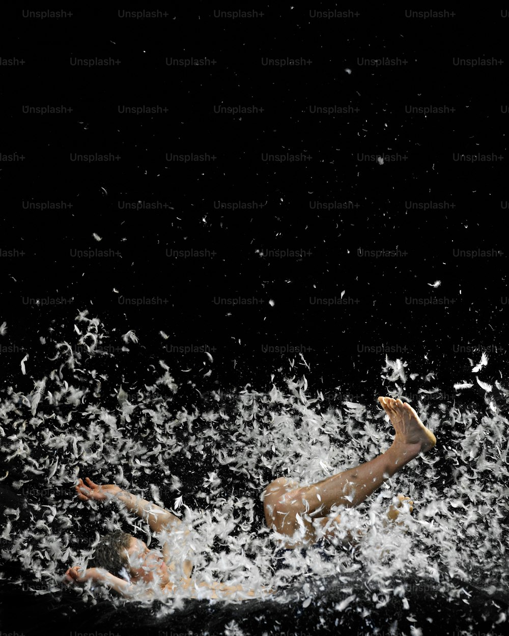 a man swimming in the water with a bunch of white confetti all around