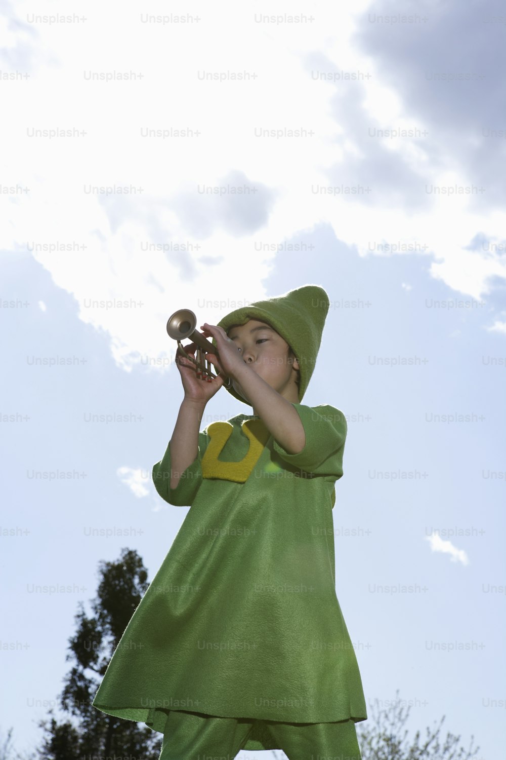 a little girl dressed in a green costume playing a trumpet