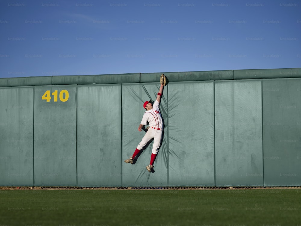 a baseball player leaning against a wall with his arm in the air