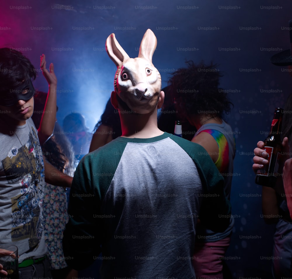 a group of people standing around with a bunny mask on