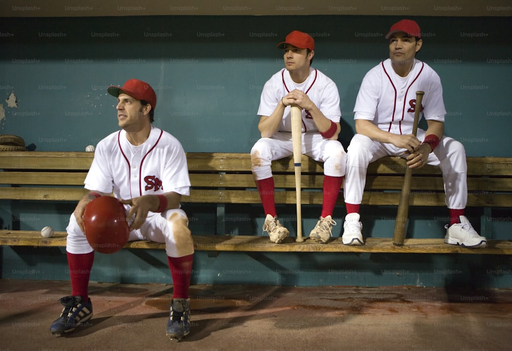three baseball players are sitting on a bench