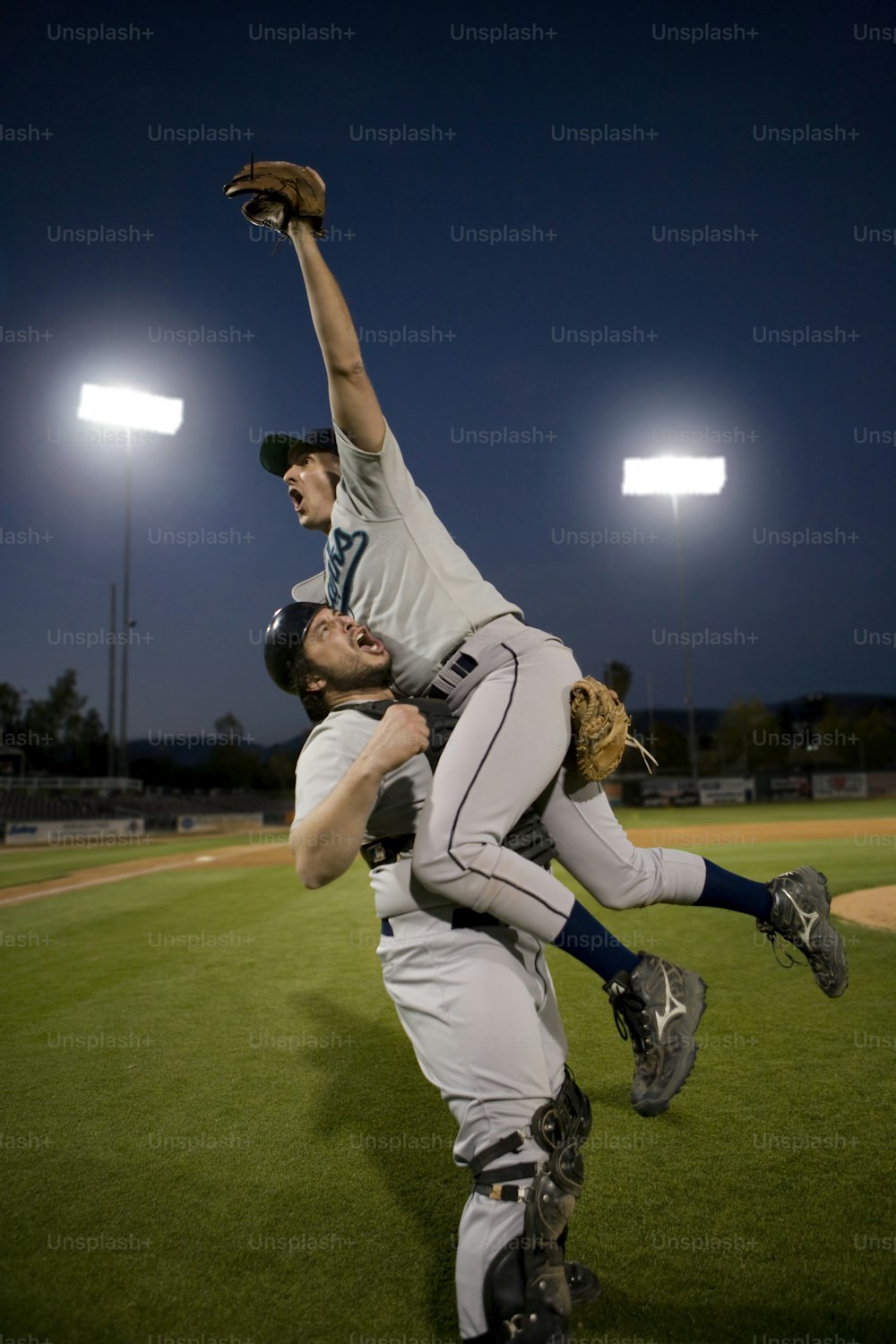 a couple of men standing on top of a baseball field