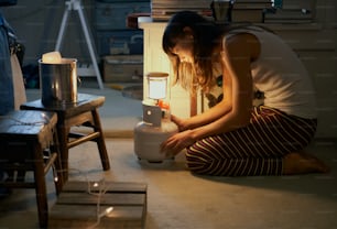 a woman sitting on the floor next to a lamp