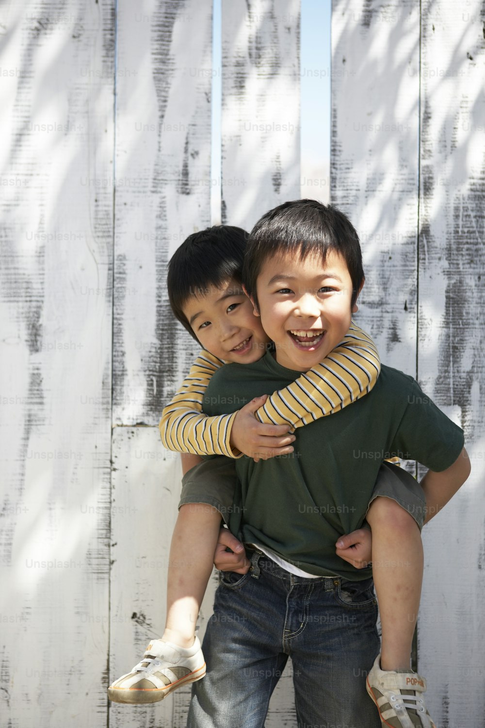 two young boys hugging each other in front of a fence
