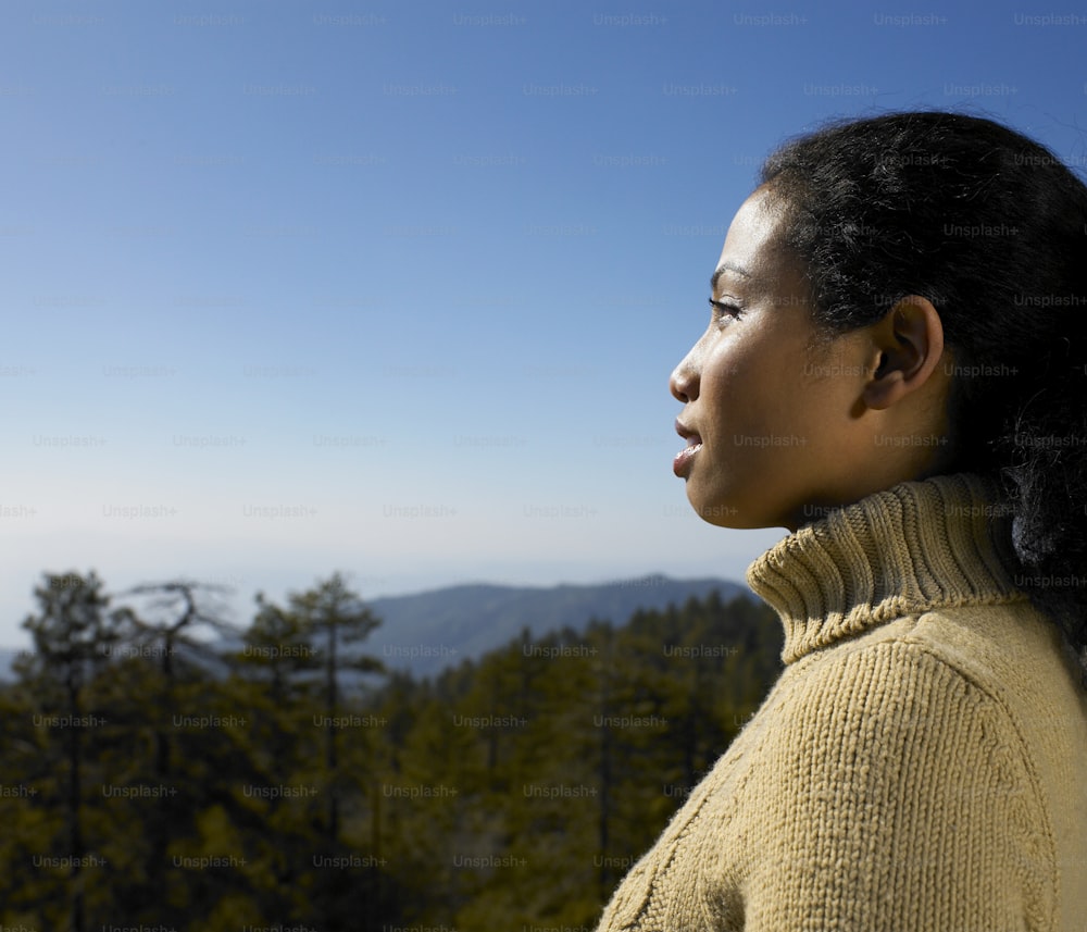 a woman standing on top of a lush green hillside