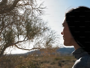 a woman standing in front of a tree