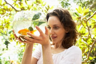 a woman holding a goldfish in a bowl