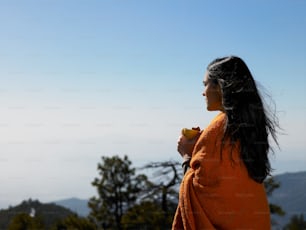 a woman in an orange robe eating a piece of fruit
