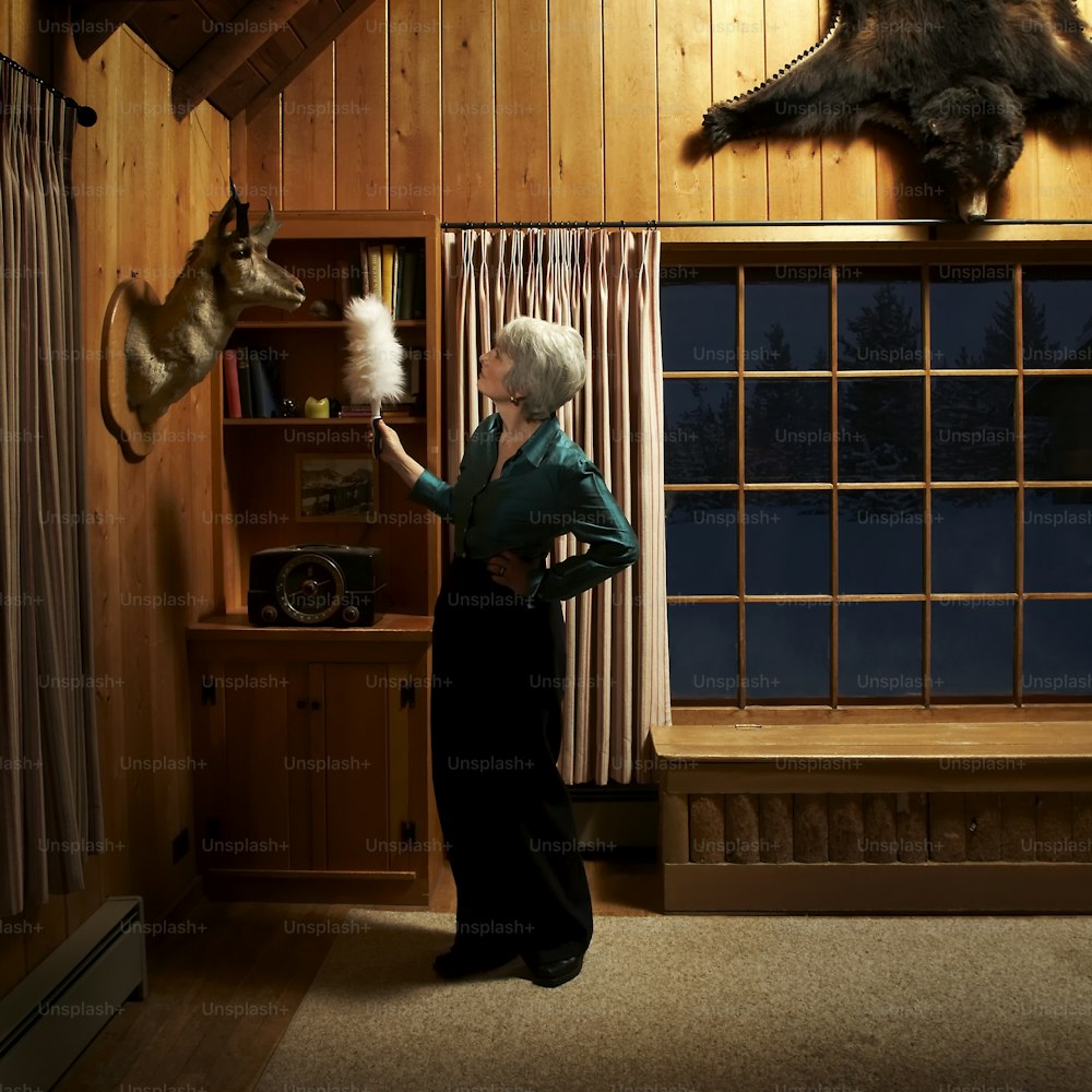 a woman standing in a room with a stuffed animal on the wall