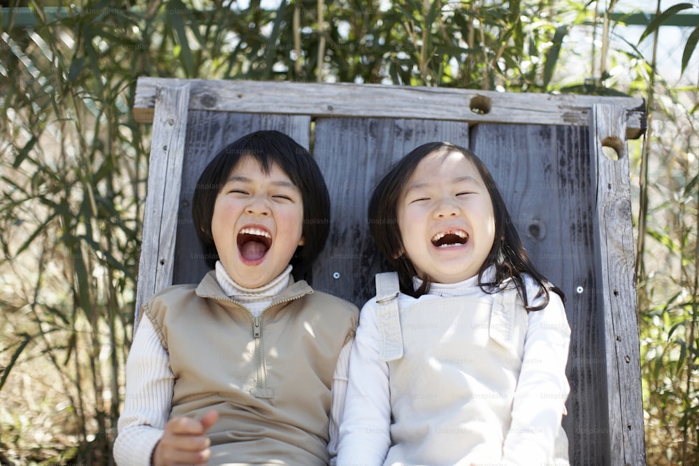 Deux jeunes filles assises sur un banc en bois, la bouche ouverte