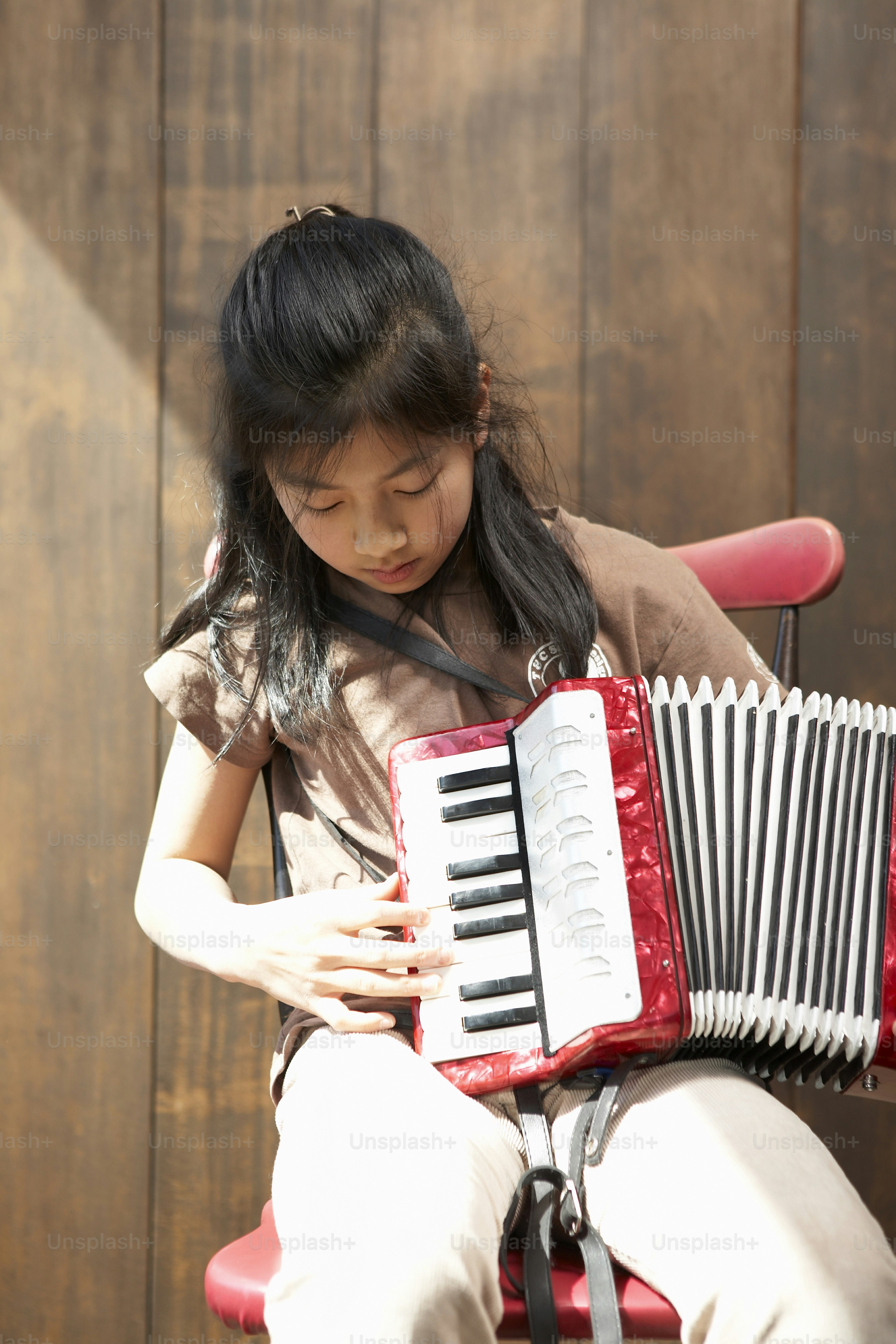 Una niña sentada en una silla tocando un acordeón