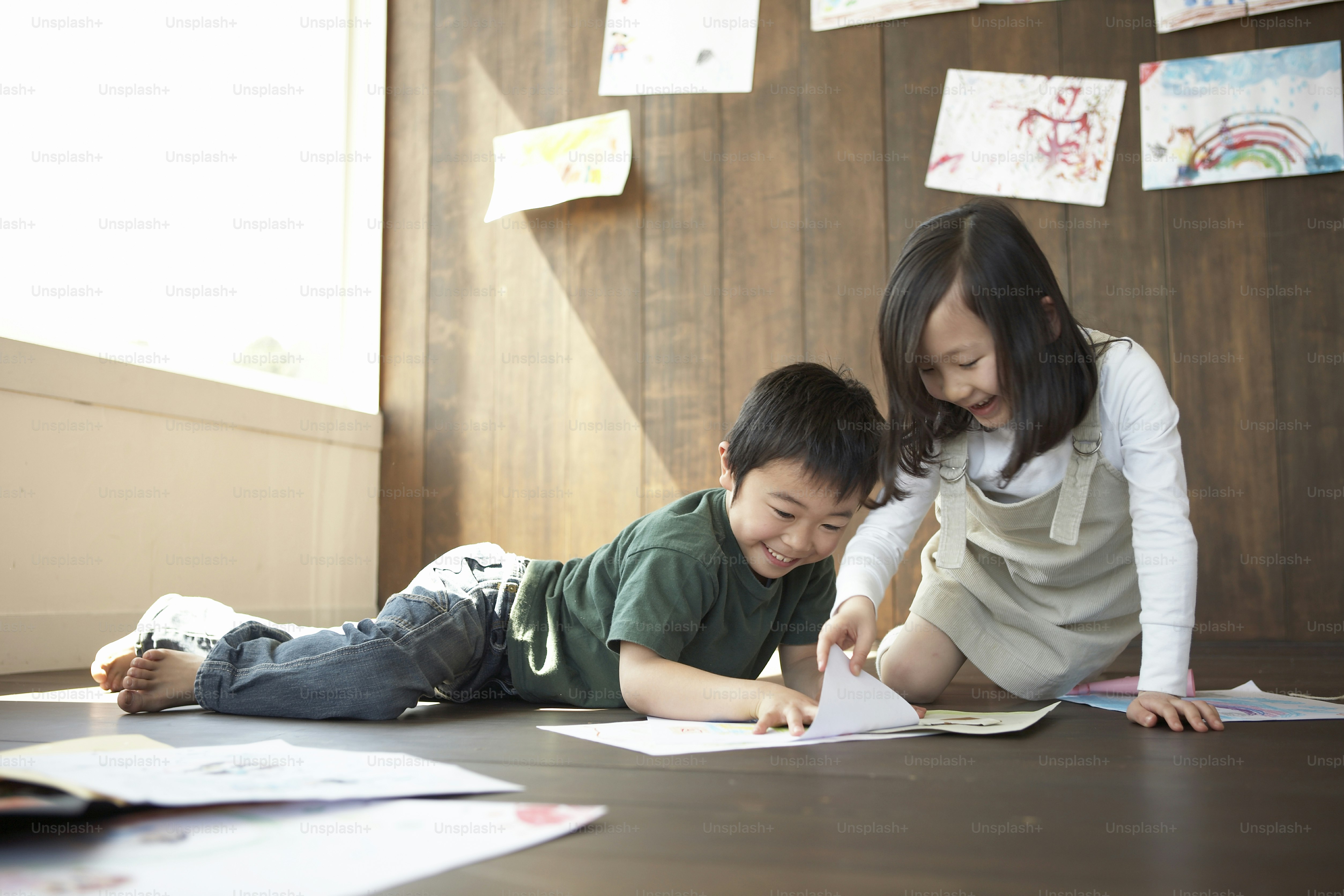 a couple of kids laying on top of a wooden floor