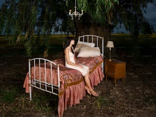 Una mujer sentada en una cama debajo de un árbol
