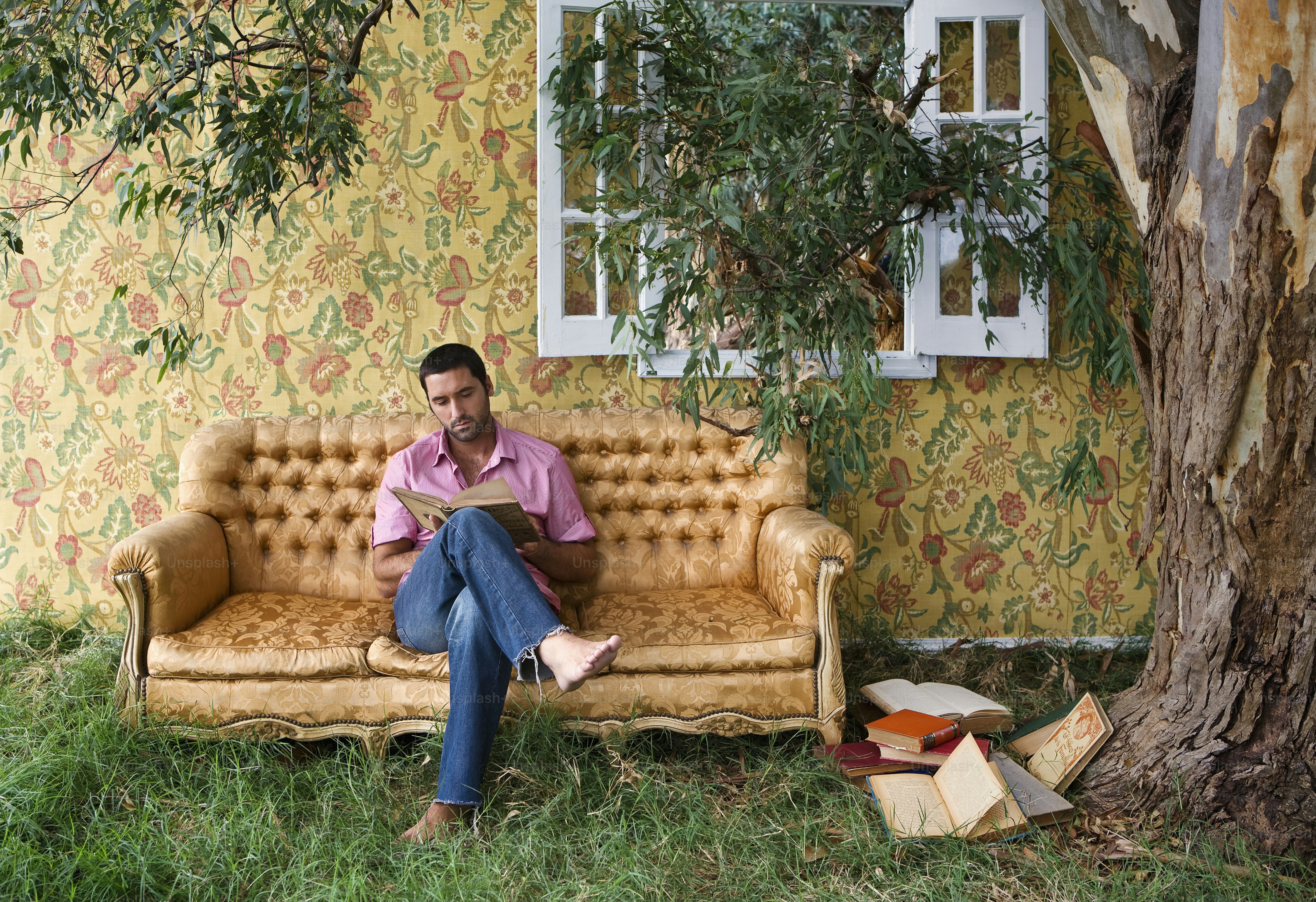 a man sitting on a couch next to a tree