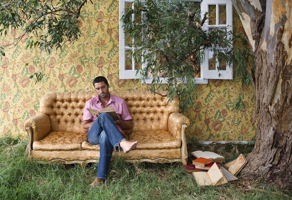 Un hombre sentado en un sofá junto a un árbol
