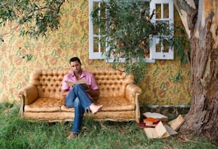 a man sitting on a couch next to a tree