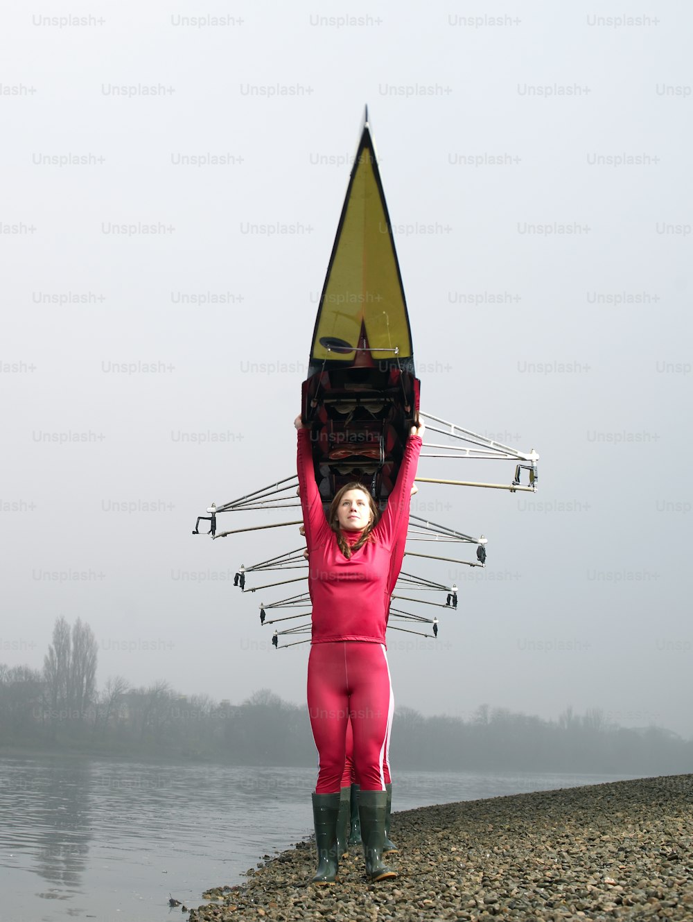 a woman in a pink wetsuit holding a surfboard over her head