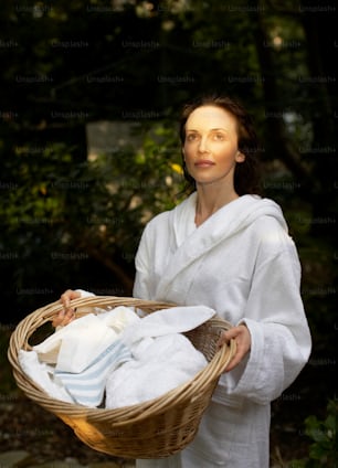 a woman holding a basket of white towels
