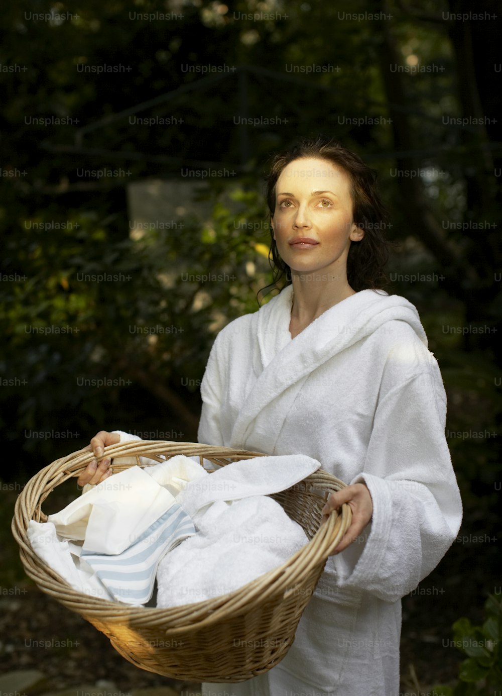 Una mujer sosteniendo una canasta de toallas blancas