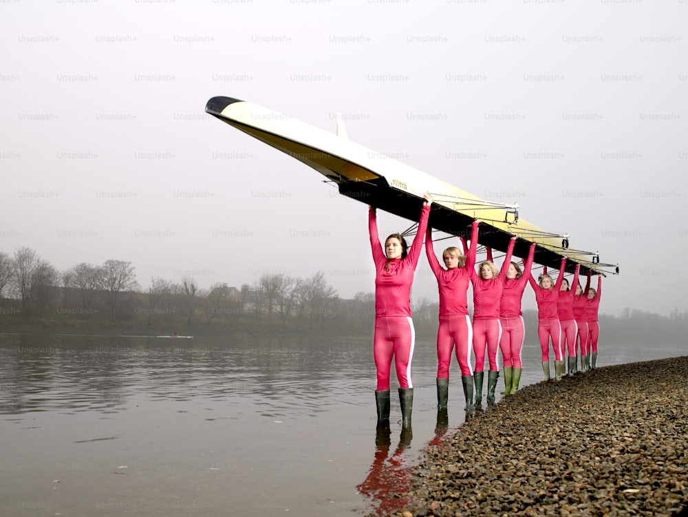 a group of people in pink suits holding a surfboard