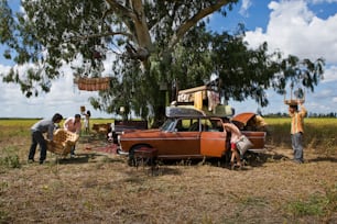 a group of people standing around a car in a field