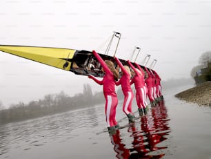 a group of people in pink suits holding onto a boat