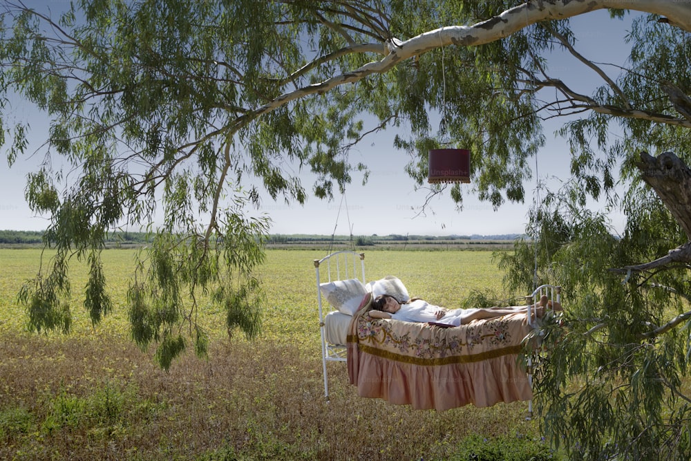 a person laying in a bed under a tree