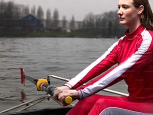 a woman in a red and white outfit rowing a boat