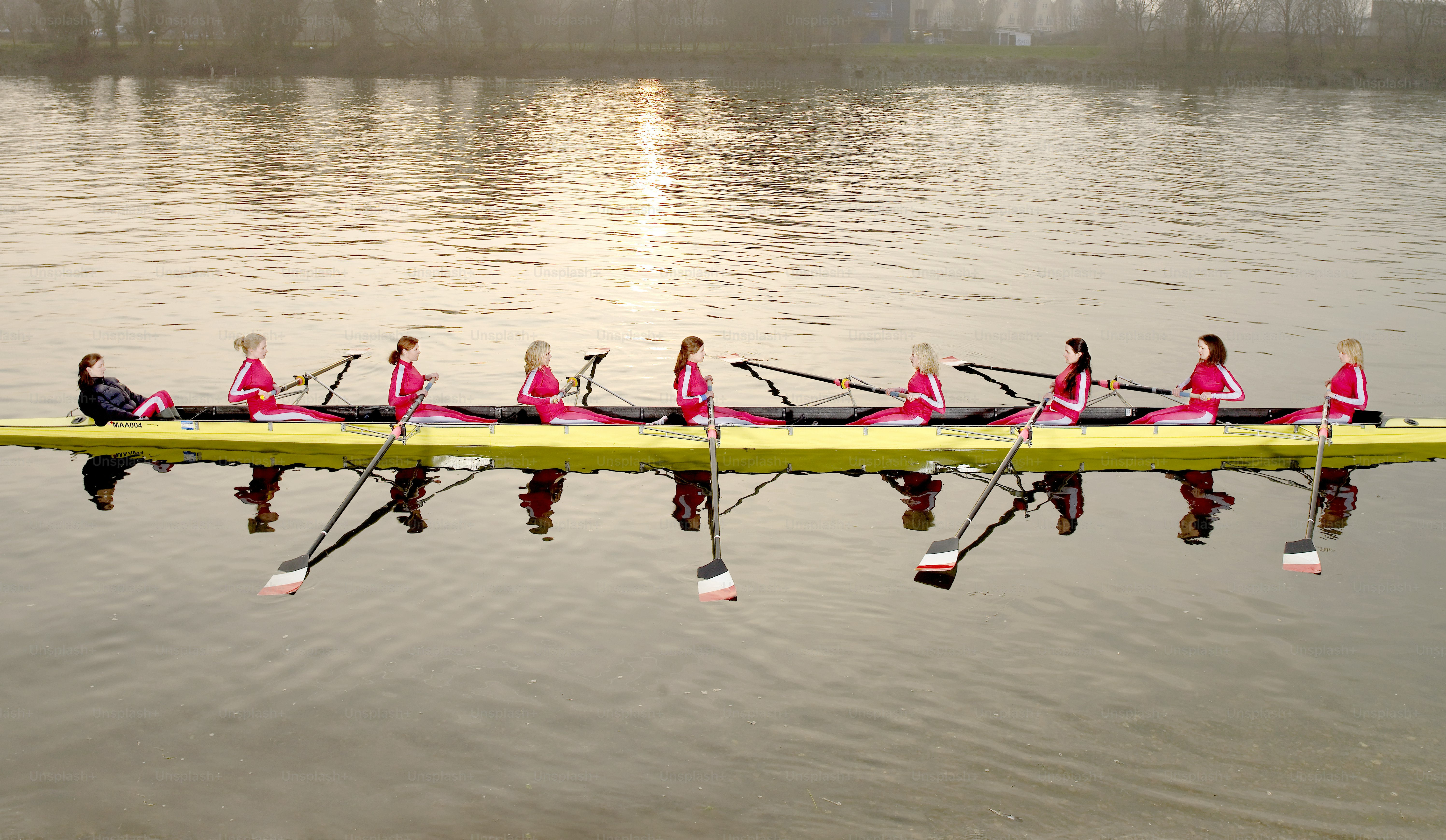 A group of people sitting on top of a yellow boat photo – Rowing Image ...