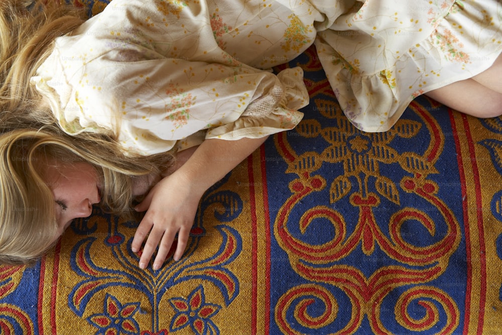 a young girl laying on a colorful carpet