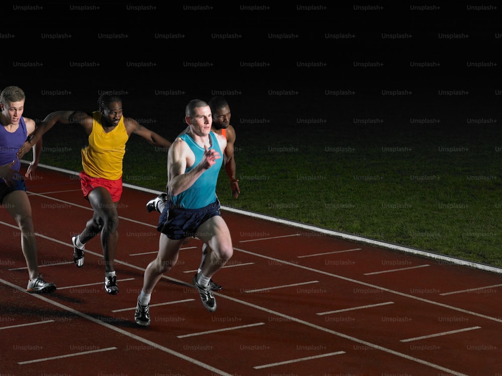 three men running on a track at night