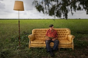 a man sitting on a couch in a field